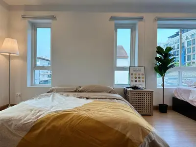 a bedroom with a bed with a yellow comforter and windows at hana villa in Bangkok