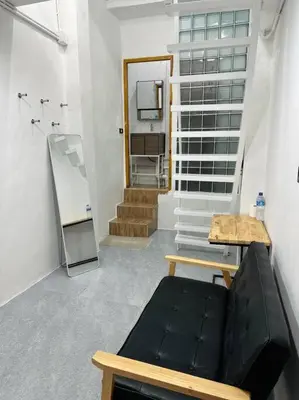 a living room with a black couch and a mirror at Megun 10 Duplex in Bangkok