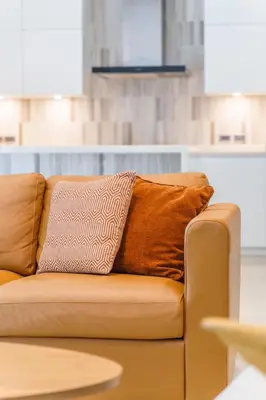 a brown couch with two pillows on it at Designer Pool Villa in Ekkamai in Bangkok