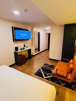 a room with a bed and a tv and a chair at Emiri Hotel - Nana Bangkok in Bangkok