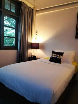 a bedroom with a large white bed with a window at ONEWAY Guest House BKK in Bangkok