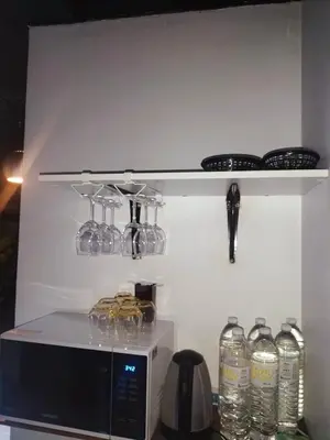 a shelf above a microwave with glasses on it at ONEWAY Guest House BKK in Bangkok