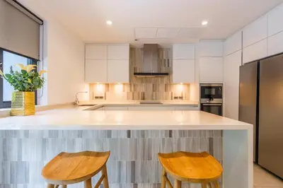 a kitchen with white cabinets and wooden stools at The Designer 49 Villa in Bangkok