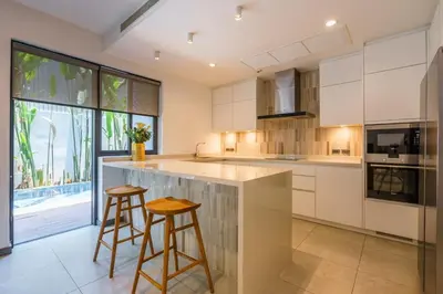 a kitchen with white cabinets and two stools at The Designer 49 Villa in Bangkok