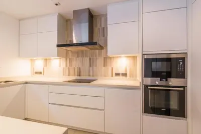 a kitchen with white cabinets and a microwave at The Designer 49 Villa in Bangkok