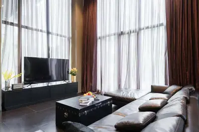 a living room with a couch and a flat screen tv at The Oasis Tranquil Escape in Bangkok