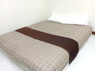 a bed in a white room with a brown and white at Bangkok Siam in Bangkok