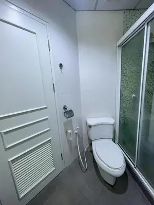 a white bathroom with a toilet and a shower at Cozy 1br walk to BTS and Airport Rail Link Close to Malls 11 in Bangkok