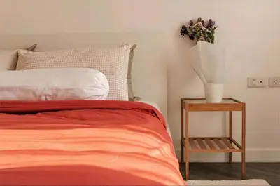 a bed with a red blanket and a table with a plant at Cozy 1br walk to BTS and Airport Rail Link Close to Malls 11 in Bangkok