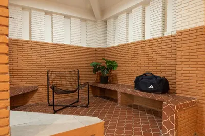 a room with a brick wall with a bench and a bag at Samyan Story Boutique Hotel in Bangkok