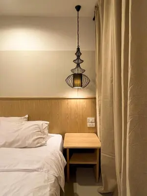 a bedroom with a bed with a table and a chandelier at Vanilla house in Nonthaburi