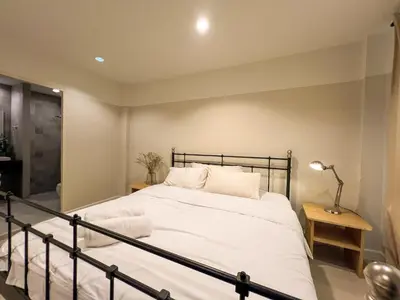 a bedroom with a bed with white sheets and a lamp at Vanilla house in Nonthaburi