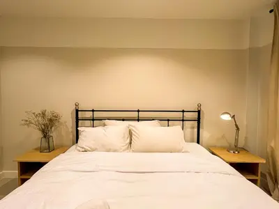 a bedroom with a bed with white sheets and pillows at Vanilla house in Nonthaburi
