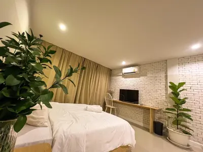 a bedroom with a white bed and a tv at Vanilla house in Nonthaburi
