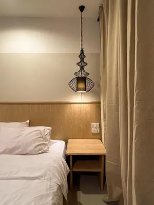 a bedroom with a bed and a table with a lamp at Vanilla house in Nonthaburi
