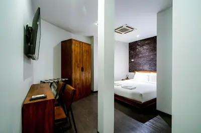 a bedroom with a bed and a desk and a tv at Elite Hotel Asok Sukhumvit 20 in Bangkok