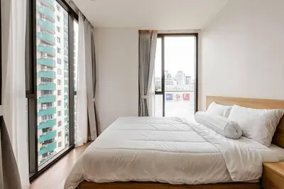 a bedroom with a large bed and a large window at Pet Friendly Modern Nest Asoke in Bangkok