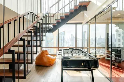 a room with a staircase and a glass table at Pet Friendly Modern Nest Asoke in Bangkok