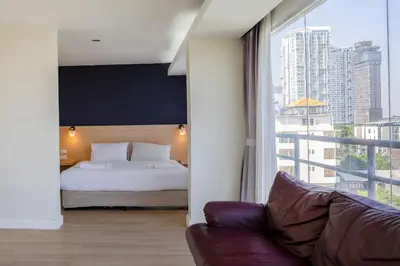 a bedroom with a bed and a couch and a large window at GP House Express Sukhumvit 81 in Bangkok