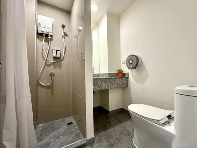 a bathroom with a shower and a toilet at The White Den Chatuchak in Bang O