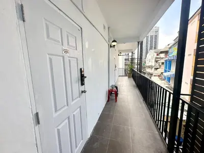 a white door on a balcony with a red stool at The White Den Chatuchak in Bang O