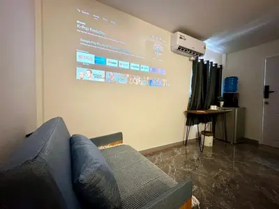 a living room with a couch and a large screen at The White Den Chatuchak in Bang O