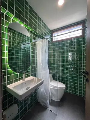 a green tiled bathroom with a sink and a toilet at Brown Brick Thonglor - Green Greenery Room in Bangkok