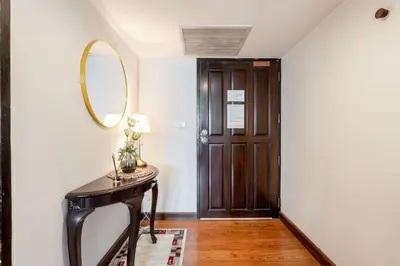 a hallway with a table and a mirror and a door at Artichoke Suite Sukhumvit, Nana BTS in Bangkok