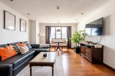 a living room with a black couch and a table at Artichoke Suite Sukhumvit, Nana BTS in Bangkok