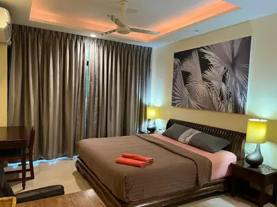 a bedroom with a large bed with a desk and a painting at Blue Chang House in Bangkok