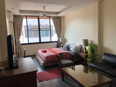 a room with a bed and a couch and a tv at Blue Chang House in Bangkok