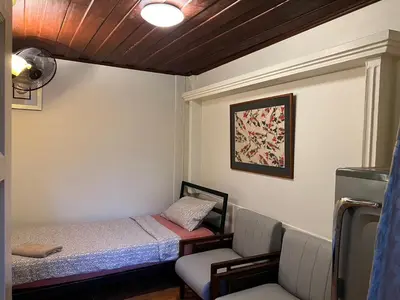 a small room with a bed and a chair at Blue Chang House in Bangkok