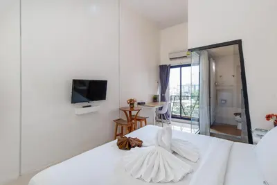 a white bedroom with a bed and a television at Baron Zotel Bangkok SHA PLUS in Bangkok