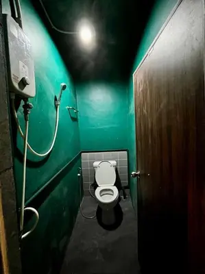 a green bathroom with a toilet in a stall at Megun capsule 150 cm in Bang O