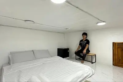 a man sitting on a table next to a bed at Megun capsule 150 cm in Bang O