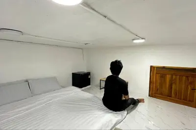 a person sitting on a bed in a room at Megun capsule 150 cm in Bang O
