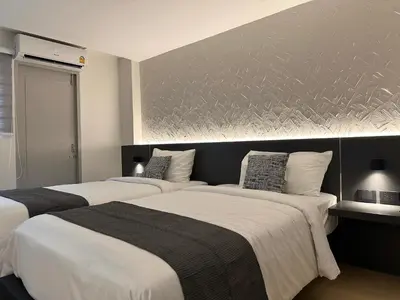 a bedroom with two beds and a wall at Lune bangkok in Bangna