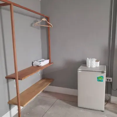 a room with a shelf next to a refrigerator at Ther Bangkoknoi Hotel in Bangkok Noi