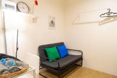 a chair in a room with a clock on the wall at Round The Clock Hostel in Samphanthawong