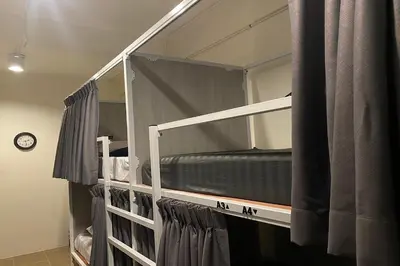 two bunk beds in a room with a clock at Round The Clock Hostel in Samphanthawong