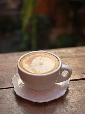 a cup of coffee on a plate on a table at Vonden Garden by Merry V in Bangkok