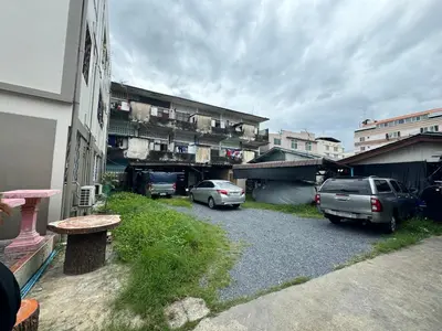 two cars parked in a parking lot next to buildings at Titi-pon Apartment Bang Khen in Bang Khen