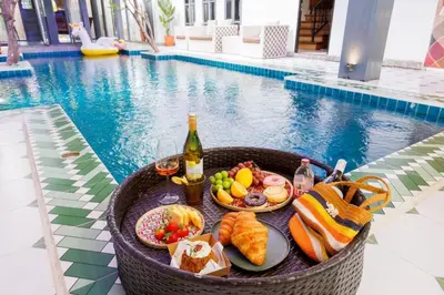 a basket filled with food and drinks next to a pool at \u83f2\u65af\u4e4b\u57ce\u66fc\u8c371200\u5e73\u7687\u5bb6\u68ee\u7cfb\u6cf3\u6c60\u6d3e\u5bf9\u522b\u5885 in Bangkok