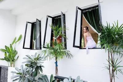 a woman looking out of a window with plants at \u8fea\u5965\u82b1\u56ed\u66fc\u8c37\u661f\u7a7a\u6cf3\u6c60\u82b1\u56ed\u6d3e\u5bf9\u522b\u5885 in Bangkok