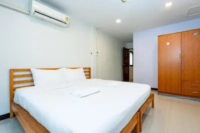 a bedroom with a large white bed and a wooden cabinet at The Hidden Giant Swing เดอะ ฮิดเด้น เสาชิงช้า in Bangkok