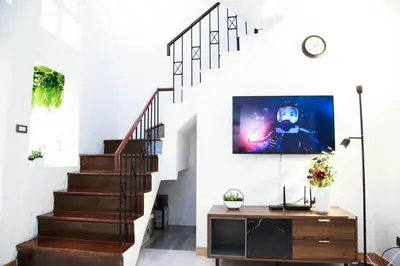 a living room with a staircase with a tv on the wall at Near BTS Bearing Skytrain- Homey living Townhome - 4 Bedrooms in Bangkok