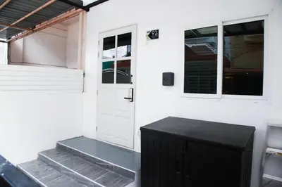a white house with a black door and windows at Near BTS Bearing Skytrain- Homey living Townhome - 4 Bedrooms in Bangkok