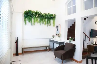 a living room with a chair and plants on the wall at Near BTS Bearing Skytrain- Homey living Townhome - 4 Bedrooms in Bangkok