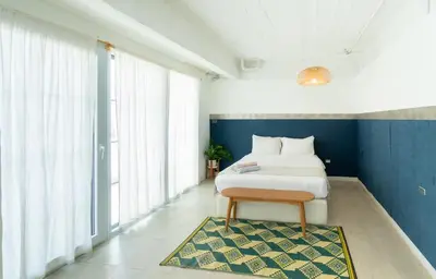a bedroom with a bed and a rug and windows at The Locals Bangkok Old Town in Bangkok