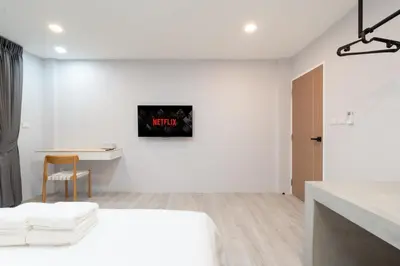 a white room with a bed and a table at Wash House Chatuchak in Bangkok